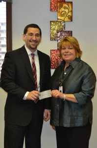 Rep. Jason Ortitay hands a donation check to Blueprints CEO Darlene Bigler